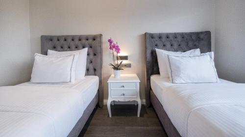 two beds with white pillows and a table with a vase of flowers at Loop Hotel Bosphorus İstanbul in Istanbul