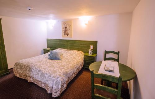 a bedroom with a bed and a table and chair at Pensiunea Ghiocelul in Avrig