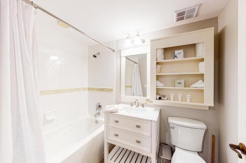 a bathroom with a sink and a toilet and a mirror at Baytowne Wharf - Pilot House #323 in Destin