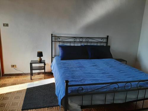 Schlafzimmer mit einem Bett mit blauer Decke und einem Beistelltisch in der Unterkunft CASA FRIDA in Canelli