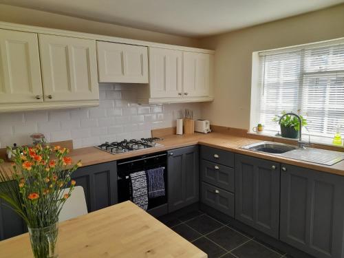 a kitchen with white cabinets and a wooden table at The Little House Louth in Louth