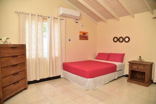 a bedroom with a bed with red sheets and a dresser at The West Village Summer House - Montego Bay in Montego Bay