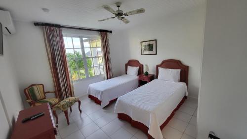 1 dormitorio con 2 camas y ventana en Sea Palms Beach Holiday, en Saint Mary