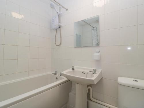bagno bianco con lavandino, vasca e servizi igienici di Lodmoor House a Weymouth