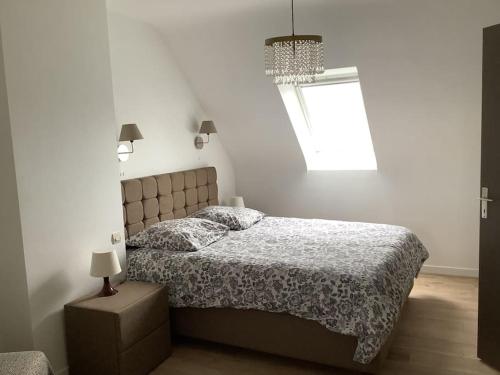 une chambre avec un lit et un lustre dans l'établissement Maison Monts d’Arree 3 chambres, à Sizun