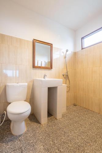 a bathroom with a toilet and a sink and a mirror at Sienna Resort in Maratua Atoll