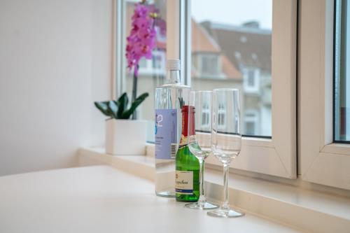 deux bouteilles de vin et des verres assis sur un rebord de fenêtre dans l'établissement Kiel-frisch renovierte Innenstadtwohnung-24h check-in, à Kiel