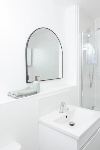 a white bathroom with a sink and a mirror at Luxury Apartment, Birmingham-Parking in Birmingham