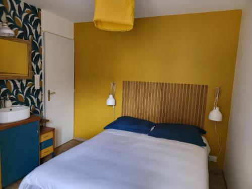 1 dormitorio con cama blanca y almohadas azules en Au Clos Des Dély-Gîtes 3 étoiles, en Mareuil