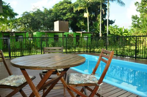 Innbox - Porto Belo في بورتو بيلو: طاولة خشبية وكرسيين بجانب المسبح