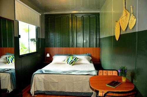 Innbox - Porto Belo في بورتو بيلو: غرفة نوم بسريرين وطاولة خشبية