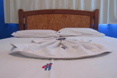 2 almohadas blancas y una manta en una cama en Hotel Cristal, en Rondonópolis