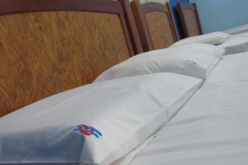a row of beds with white sheets and a red and blue logo at Hotel Cristal in Rondonópolis