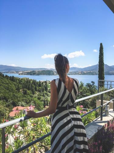 a woman in a striped dress looking out at the water at Thealos Village aparthotel Lefkada in Lygia