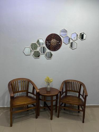 a table and two chairs and a plate on a wall at Raudah Homestay in Kota Bharu