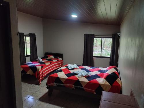 two beds in a room with two windows at Nacientes Lodge in Bijagua