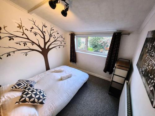 - une chambre avec un lit et un arbre sur le mur dans l'établissement House near restaurants, park and pubs, perfect for pets!, à Bristol