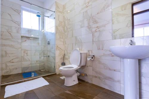 een badkamer met een toilet, een wastafel en een douche bij Lathembo Serviced Apartments in Nairobi