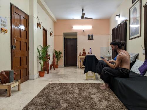 加爾各答的住宿－Guten Tag Kolkata，坐在沙发上的女人看着她的手机
