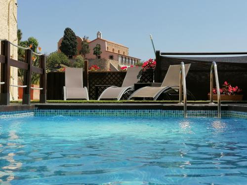 uma piscina com cadeiras brancas e uma piscina em Cal Music B&B em Premia de Dalt