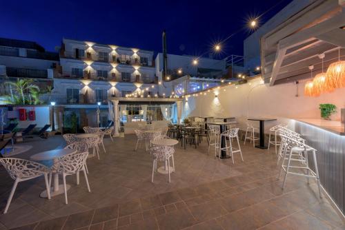 een patio met tafels en stoelen in de nacht bij Hotel Boutique Sibarys - Adults Recommended in Nerja