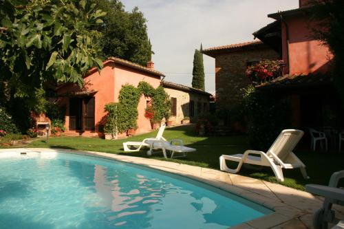 uma piscina com duas espreguiçadeiras e uma casa em Casa Rosada em Lucignano