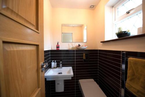 a bathroom with a sink and a toilet and a window at Luxury 6 bedroom house with parking - Northwood in Northwood