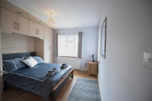 Un dormitorio con una cama azul y una ventana en Luxury 6 bedroom house with parking - Northwood, en Northwood