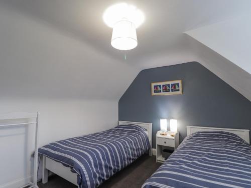a bedroom with two beds and a blue wall at 20 South High Street in Portsoy