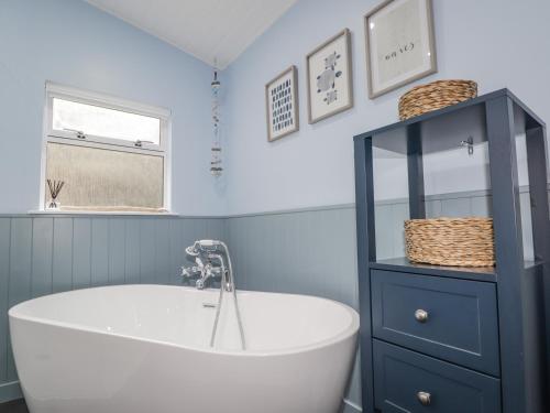 a bathroom with a white tub and a blue cabinet at 20 South High Street in Portsoy