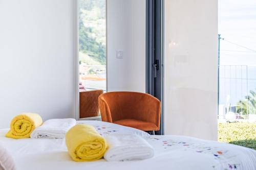 a bedroom with two beds with yellow towels and a chair at Villa Plumeria in Arco da Calheta