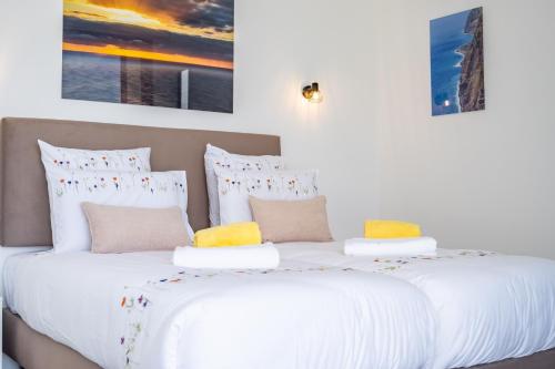 two beds in a bedroom with white sheets and yellow pillows at Villa Plumeria in Arco da Calheta