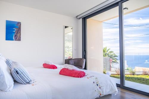 two beds with red pillows in a room with a window at Villa Plumeria in Arco da Calheta