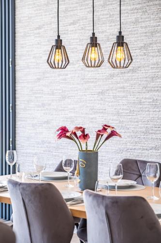 a dining room with a table with chairs and lights at Villa Plumeria in Arco da Calheta