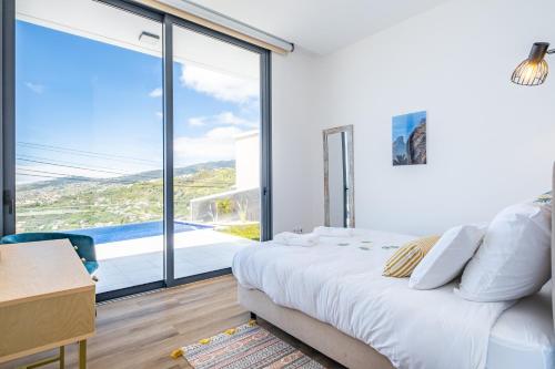 a bedroom with a bed and a large window at Villa Plumeria in Arco da Calheta