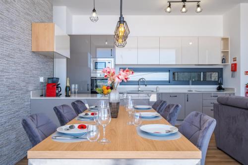 a dining room with a table and chairs and a kitchen at Villa Plumeria in Arco da Calheta