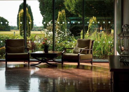 two chairs and a table in a room with a garden at Castlemartyr Resort Hotel in Castlemartyr
