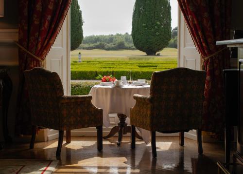 a dining room with a table and chairs and a window at Castlemartyr Resort Hotel in Castlemartyr