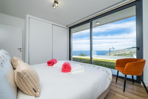ein Schlafzimmer mit einem weißen Bett und einem großen Fenster in der Unterkunft Villa Camelia in Arco da Calheta