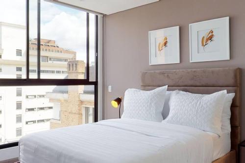1 dormitorio con cama blanca y ventana grande en Apartamento 601 kappadoccia, en Bogotá