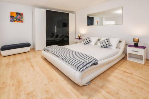 a large white bed in a room with wooden floors at Spacious 2BD, fully equipped for a relaxing holiday in Split