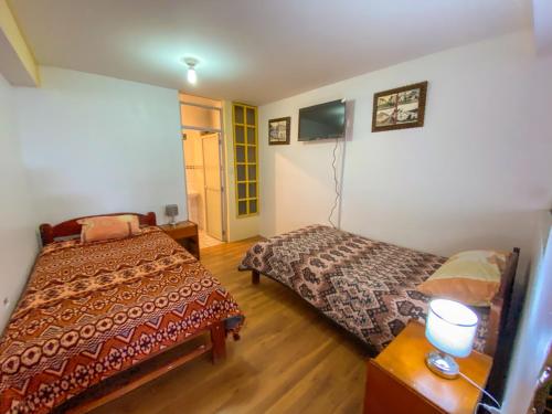 a bedroom with two beds and a tv in it at Sueños Sambleños in Cusco