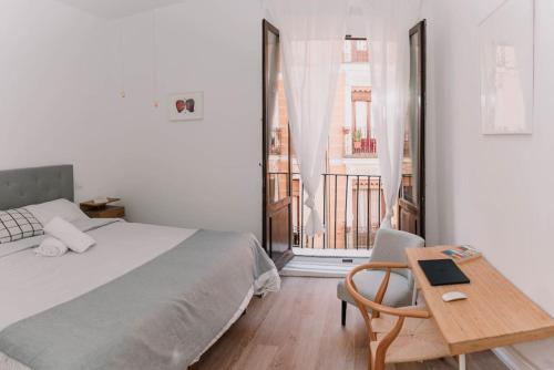 a bedroom with a bed and a table with a laptop at Stylish apartment in the centre of Madrid-Malasaña in Madrid