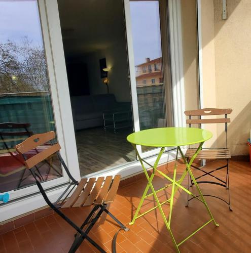 une table et des chaises vertes dans une chambre avec fenêtre dans l'établissement Large studio in the center of town near the beach, à Saint-Aygulf