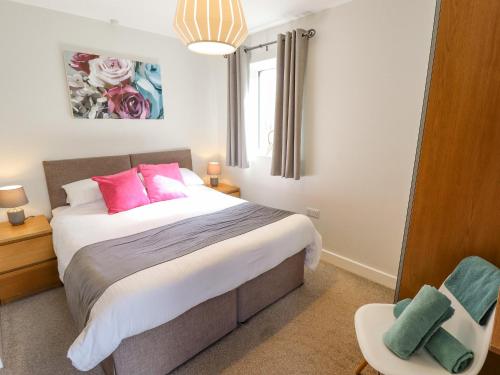 Un dormitorio con una cama con almohadas rosas y una silla en Lily-pad Lodge, en Thorpe on the Hill