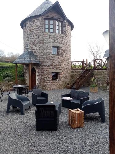 a stone building with couches and tables in a yard at La Tour de Ver Gite atypique Possibilité table d'hôtes sur réservation in Ver