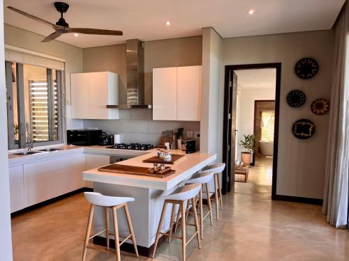 a kitchen with white cabinets and a island with bar stools at VillaTwo@Tsai-Tsai in Vilanculos