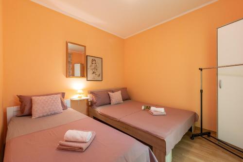 2 Betten in einem Zimmer mit orangefarbenen Wänden in der Unterkunft Michael's House in Vela Luka
