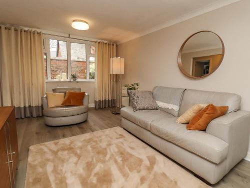 a living room with a couch and a mirror at Jasmine Cottage in Lytham St Annes