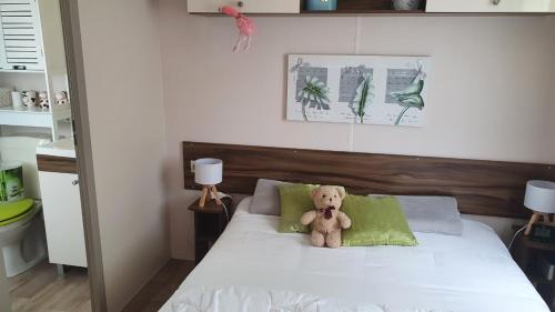 un ours en peluche assis sur un lit dans l'établissement Aux flamants rose, à Saint-Jean-de-Monts